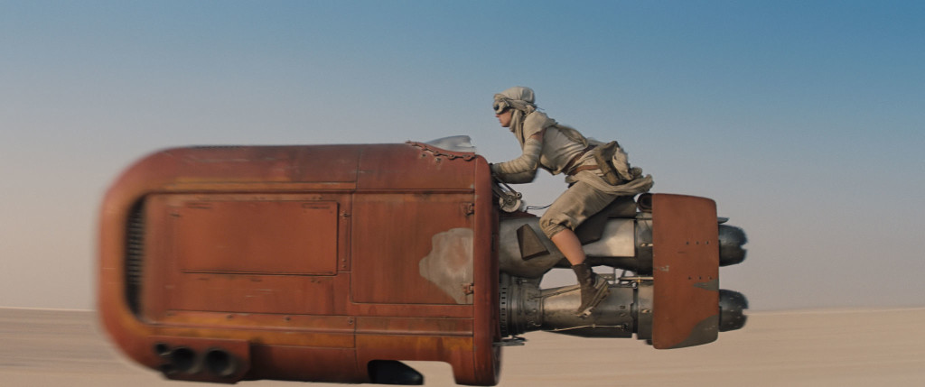 Rey zooms on her speeder through Jakku's desert